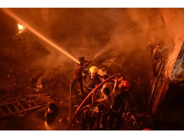 In this Wednesday, Feb. 20, 2019, photo, firefighters try to douse flames in Dhaka, Bangladesh.