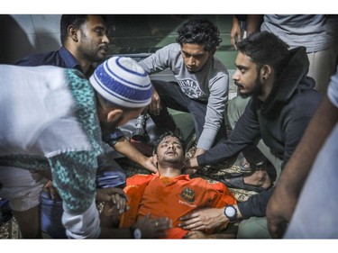 Locals help a Bangladeshi firefighter who got unconscious for a while, while trying to douse flames of a smoldering fire in a building in Dhaka, Bangladesh, Thursday, Feb. 21, 2019. The devastating fire raced through buildings in an old part of Bangladesh's capital and killed scores of people.