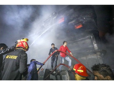 Locals and firefighters douse flames of a smouldering fire in a building in Dhaka, Bangladesh, Thursday, Feb. 21, 2019.