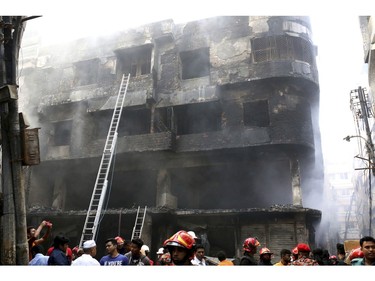 Locals and firefighters gather around buildings which caught fire late night in Dhaka, Bangladesh, Thursday, Feb. 21, 2019.