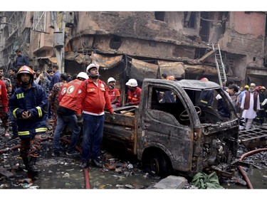 Locals and firefighters gather around buildings that caught fire late Wednesday in Dhaka, Bangladesh, Thursday, Feb. 21, 2019.