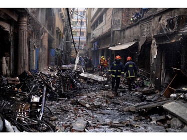 Firefighters gather around buildings that caught fire late Wednesday night in Dhaka, Bangladesh, Thursday, Feb. 21, 2019.