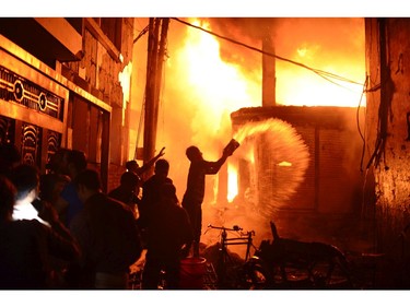 In this Wednesday, Feb. 20, 2019, photo, firefighters and local people help douse a fire in Dhaka, Bangladesh.