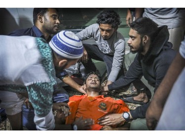 Locals help a Bangladeshi firefighter who lost consciousness briefly while trying to douse flames of a smoldering fire in a building in Dhaka, Bangladesh, Thursday, Feb. 21, 2019.