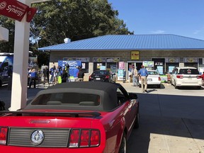 In this Wednesday, Oct. 24, 2018 file photo, media, at left, record people entering the KC Mart in Simpsonville, S.C., after it was announced the winning Mega Millions lottery ticket was purchased at the store.  (AP Photo/Jeffrey Collins, File)