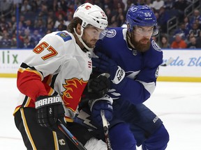 Calgary Flames' Michael Frolik, left, of the Czech Republic, goes into the boards for a loose puck against Tampa Bay Lightning's Braydon Coburn during the first period of an NHL hockey game Tuesday, Feb. 12, 2019, in Tampa, Fla.