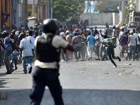 Demonstrators flee as Haitian Police open fire during protests in the Haitian capital Port-au-Prince, Wednesday, Feb. 13, 2019.