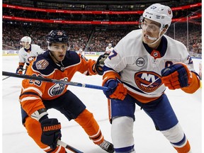 New York Islanders' Anders Lee (27) and Edmonton Oilers' Darnell Nurse (25) battle for the puck during third period NHL action in Edmonton on Thursday, Feb. 21, 2019.