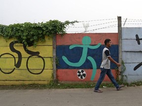 A man walks past sports murals originally painted on a wall as promotional tools for the 2018 Asian Games in Jakarta, Indonesia, Tuesday, Feb. 19, 2019. Indonesia has officially joined bidding to host the 2032 Olympics following its success staging the Asian Games last year, the deputy chairman of its national Olympic committee said Tuesday, highlighting the rising ambitions of the giant but perennially underperforming Southeast Asian nation.