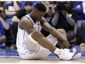 Duke's Zion Williamson sits on the floor following a injury during the first half of an NCAA college basketball game against North Carolina, in Durham, N.C., Wednesday, Feb. 20, 2019.