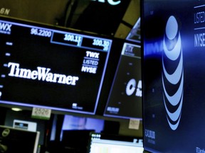 In this June 13, 2018, file photo, the logos for Time Warner and AT&T appear above alternate trading posts on the floor of the New York Stock Exchange.