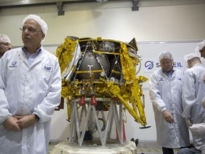In this Monday, Dec. 17, 2018 file photo, technicians stand next to the SpaceIL lunar module, an unmanned spacecraft, on display in a special clean room during a press tour of their facility near Tel Aviv, Israel. SpaceIL and the state-owned Israel Aerospace Industries plan to launch the lunar lander on a SpaceX Falcon rocket Thursday night, Feb. 21, 2019, from Cape Canaveral, Fla.