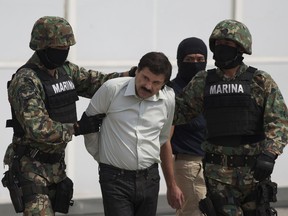 In this Saturday, Feb. 22, 2014 file photo, Joaquin "El Chapo" Guzman, center, is escorted to a helicopter in handcuffs by Mexican navy marines at a hanger in Mexico City, after he was captured overnight in the beach resort town of Mazatlan.