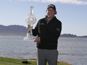 Phil Mickelson poses with his trophy on the 18th green of the Pebble Beach Golf Links after winning the AT&T Pebble Beach Pro-Am golf tournament Monday, Feb. 11, 2019, in Pebble Beach, Calif.