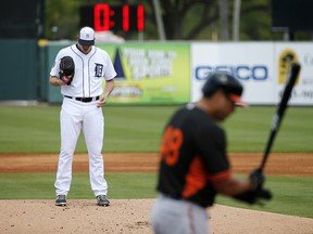 In this March 3, 2015, file photo, a clock counts down as Detroit Tigers pitcher Kyle Lobstein, left, prepares to deliver his pitch to Baltimore Orioles' Matt Tulasosopo during a spring training game in Lakeland, Fla. (AP Photo/Gene J. Puskar, File)