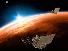 This illustration made available by NASA on March 29, 2018 shows the twin Mars Cube One (MarCO) spacecraft flying over Mars with Earth and the sun in the distance.