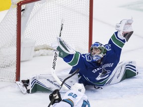 San Jose Sharks' Kevin Labanc, bottom, scores against Vancouver Canucks goalie Michael DiPietro during the second period of an NHL hockey game, Monday, Feb. 11, 2019, in Vancouver, British Columbia. (Darryl Dyck/The Canadian Press via AP) ORG XMIT: VCRD215