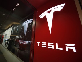 In this Feb. 9, 2019, file photo, a sign bearing the company logo is displayed outside a Tesla store in Cherry Creek Mall in Denver. (AP Photo/David Zalubowski, File)