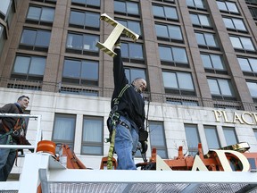 In this March 16, 2016 file photo, one of the workmen holds up the letter "T" as they remove the letters from a building formerly known as Trump Place in New York. (AP Photo/Seth Wenig, File)