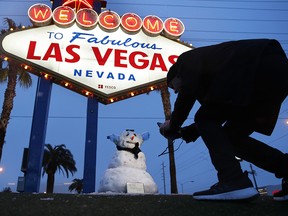 A man, who declined to give his name, takes a picture of a small snowman at the "Welcome to Fabulous Las Vegas" sign along the Las Vegas Strip, Thursday, Feb. 21, 2019, in Las Vegas. (AP Photo/John Locher)