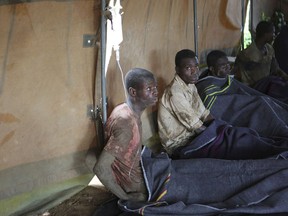 Survivors of artisanal miners sit in a tent after rains flooded mines on the outskirts of Kadoma, west of Harare, Zimbabwe, Saturday, Feb, 16, 2019. About 40 people were trapped underground, said a police spokesman.