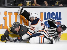 Tomas Nosek #92 of the Vegas Golden Knights and Darnell Nurse #25 of the Edmonton Oilers crash into linesman Derek Nansen as they go after the puck in the second period of their game at T-Mobile Arena on March 17, 2019 in Las Vegas, Nevada.