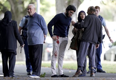 People stand across the road from a mosque in central Christchurch, New Zealand, Friday, March 15, 2019.