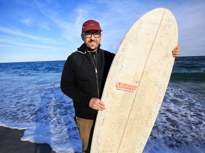In this undated photo, Korey Nolan of Hampton Falls, N.H., stands with the surfboard he made using hundreds of Dunkin' Donuts coffee cups and other single-use materials.