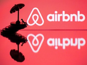 In this file illustration photo taken on August 29, 2018 taken in Paris shows a toy umbella and a figurine on coins next to the logo of  rental website Airbnb.