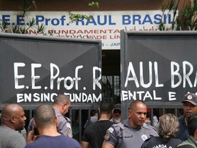 Police officers guard the entrance of the Raul Brasil State School in Suzano, Brazil, Wednesday, March 13, 2019.