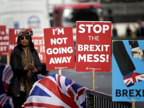 A tourist takes a selfie next to placards placed by anti-Brexit supporters stand opposite the Houses of Parliament in London, Monday, March 18, 2019.