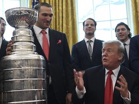 President Donald Trump, second from right, is surrounded by members of the 2018 Stanley Cup champion Washington Capitals in the Oval Office of the White House in Washington, Monday, March 25, 2019. (AP Photo/Susan Walsh)