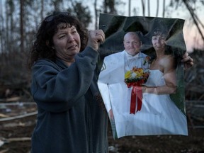 Carol Dean holds up her wedding photo to show family members after finding it in the rubble of the home she shared with husband, David Wayne Dean, who died when a tornado destroyed the house in Beauregard, Ala., Monday, March 4, 2019.