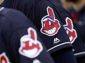 In this June 19, 2017 file photo, members of the Cleveland Indians wear uniforms featuring mascot Chief Wahoo as they stand on the field for the national anthem before a game against the Baltimore Orioles in Baltimore.