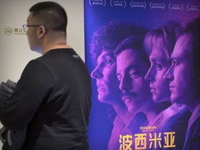 A customer walks past a movie poster for the film "Bohemian Rhapsody" at a movie theater in Beijing, Wednesday, March 27, 2019. Moviegoers in China say the version of the "Bohemian Rhapsody" shown in Chinese theaters erases mentions of Freddie Mercury's sexuality. The biopic on the lead singer of the British rock band Queen omitted a same-sex kiss and lacked scenes in which Mercury reveals he's not straight and has AIDS.