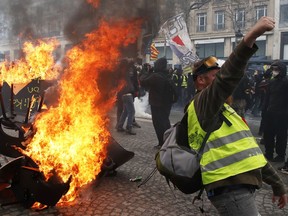 A protester shouts slogans in front of a barricade on fire during a yellow vests demonstration Saturday, March 16, 2019 in Paris.