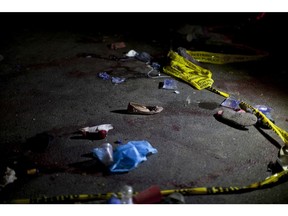 Yellow police tape and shoes lay on the ground in the place where an accident occurred, in Nahuala, Guatemala, early Thursday, March 28, 2019. A large truck slammed into a crowd gathered on a dark highway in western Guatemala, killing over a dozen people and leaving bodies scattered on the roadway, firefighters said.