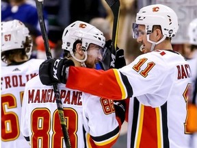 Calgary Flames' Andrew Mangiapane (88) and teammate Mikael Backlund (11) celebrate their teams win after NHL hockey action against the Vancouver Canucks, in Vancouver on Saturday, March 23, 2019.