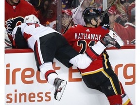 Ottawa Senators' Filip Chlapik, left, is checked into the bench by Calgary Flames' Garnet Hathaway during first period NHL hockey action in Calgary, Thursday, March 21, 2019.