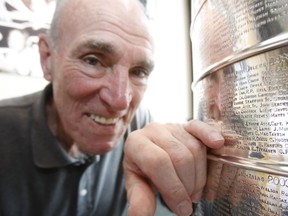 Hall of Fame defenceman Harry Howell points to his name on the Stanley Cup.