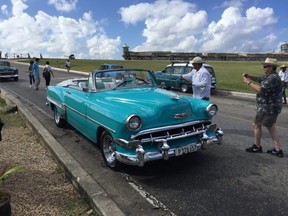 Tourists rush to snap pictures of a vintage Chevy during a visit to El Morro fortress. Classic cars are one of Cuba's signature sights. Many have been restored for use as tourist taxis. Visitors will also see vintage Ladas in Old Havana, but the boxy Russian-built autos are not nearly as attractive as the American-built beauties.