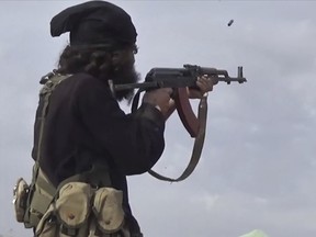 This frame grab from video posted online Monday, March 18, 2019, by the Aamaq News Agency, a media arm of the Islamic State group, shows an IS fighter firing his weapon during clashes with the U.S.-backed Syrian Democratic Forces (SDF). (Aamaq News Agency via AP)