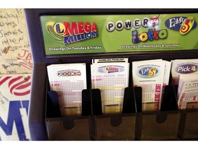 In this Tuesday, Oct. 23, 2018 file photo, lottery forms for Louisiana Mega Millions, Powerball and other lottery games fill the drawer at The World Bar and Grill, in Delta, La., a few miles from the Mississippi-Louisiana state line. Lottery officials say two tickets have won the estimated $750 million Powerball jackpot. Powerball officials say tickets purchased in Iowa and New York match all six numbers in the drawing on Saturday night, Oct. 27. The jackpot is the fourth-largest in U.S. history.