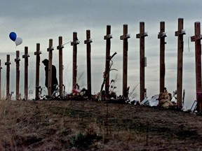 In this April 28, 1999, file photo, a woman stands among 15 crosses posted on a hill above Columbine High School in Littleton, Colo.