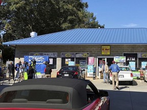In this Oct. 24, 2018, file photo, media, at left, record people entering the KC Mart in Simpsonville, S.C., after it was announced the winning Mega Millions lottery ticket was purchased at the store.