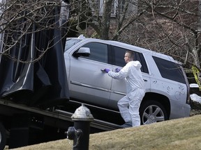 Crime scene investigators load a car that appears to have been checked for fingerprints onto a flatbed truck in the Staten Island borough of New York, Thursday, March 14, 2019. (AP Photo/Seth Wenig)