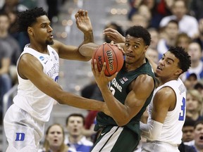 Michigan State forward Xavier Tillman looks to pass the ball as he is covered by Duke centre Marques Bolden  guard Tre Jones during the first half of an NCAA men's East Regional final college basketball game in Washington, Sunday, March 31, 2019.