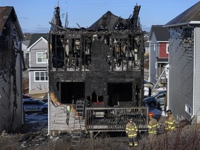 Firefighters investigate following a house fire in the Spryfield community in Halifax on Tuesday, February 19, 2019. Three weeks after a fast-moving house fire killed seven young members of a Syrian refugee family, the charred remains of their home in suburban Halifax has been torn down.