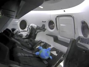 This photo provided by SpaceX shows a life-size test dummy along with a toy that is floating in the Dragon capsule as the capsule made orbit on Saturday, March 2, 2019.