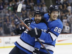 Winnipeg Jets' Mathieu Perreault (left) and Jack Roslovic celebrate Perreault's go ahead goal on Calgary Flames goaltender Mike Smith in Winnipeg on Saturday. (The Canadian Press)